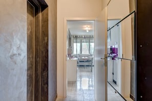 Enter a serene space with a large mirror and door, complemented by a window with curtains and a table with chairs.