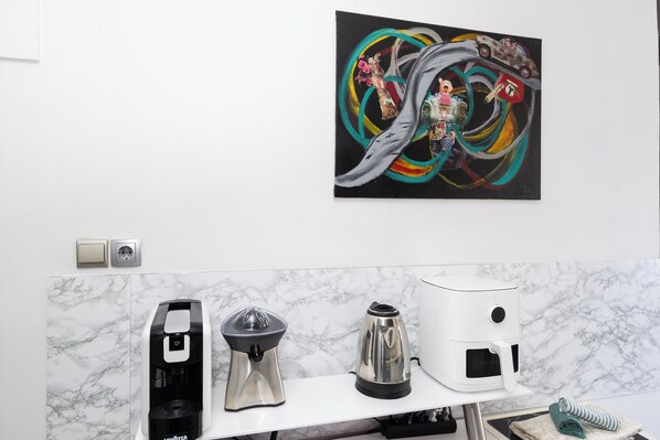 A kitchen with a marble backsplash, a coffee maker, a kettle, and a toaster.