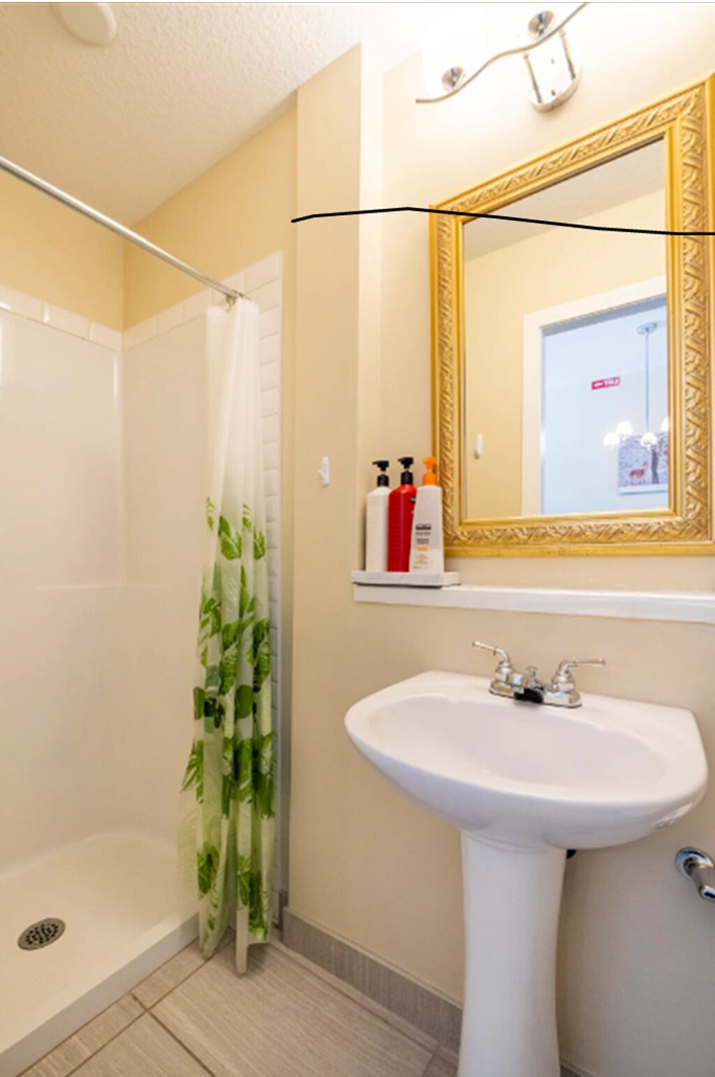 Ein Badezimmer mit Dusche, Waschbecken und einem Spiegel mit Zierrahmen.