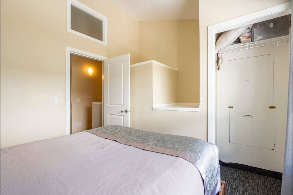 Une chambre d’hôtel avec un lit, une armoire, une porte et une petite fenêtre.