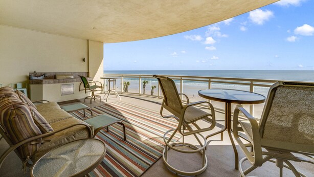A balcony with a sofa, chairs, and a small table, overlooking the ocean. - WOW! Gorgeous Oceanfront Luxury Condo (Daytona Beach)