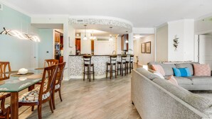 A modern kitchen with a curved island, bar stools, and pendant lighting. - WOW! Gorgeous Oceanfront Luxury Condo (Daytona Beach)