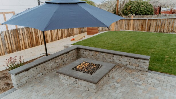 Un espace patio avec un foyer et un grand parasol.