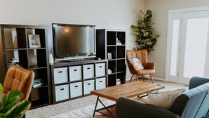 Un salon équipé d’un téléviseur, de meubles de rangement, d’une table basse et de sièges.