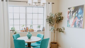 Un coin repas avec une table ronde, des chaises de couleur turquoise, un vase et une plante en pot.