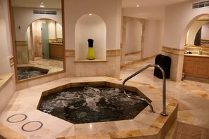 Zona de spa con hidromasaje, un espejo y un lavabo.
