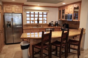 A kitchen with a stainless steel refrigerator, a built-in dishwasher, a granite countertop, and wooden cabinetry. - Cabo Lands End View 2200 sq ft Villa 1306, private beach, 5-star resort, pools (Cabo San Lucas)