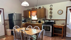 A kitchen with wooden cabinets, a refrigerator, a stove, and a dining table with chairs. - Patoka Lake Deluxe with Jacuzzi #17 at Patoka 4 Seasons Resort (Eckerty)