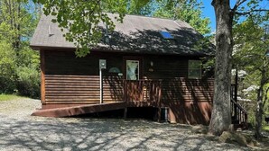 A wooden cabin with a porch, surrounded by trees and gravel. - Patoka Lake Deluxe with Jacuzzi #17 at Patoka 4 Seasons Resort (Eckerty)