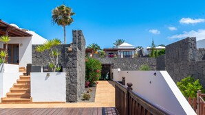 Eine moderne Villa mit Natursteinfassade, Holzterrasse und freiem Blick auf die umliegende Landschaft.