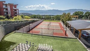 Un espace extérieur dédié aux sports, comprenant un terrain de basket-ball, un court de tennis et un green d’entraînement au putting.