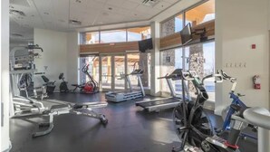 Une salle de sport équipée de tapis de course, de vélos d’appartement et d’appareils de musculation.