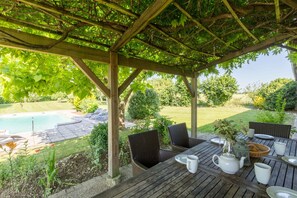 A covered patio with a pool, outdoor furniture, and a garden view. - Heated pool, single-storey, rural location. Near restaurants and historic towns (Pardaillan)