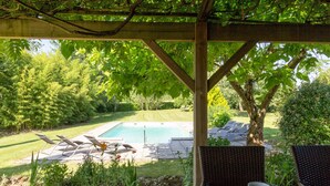 Eine überdachte Terrasse mit Pool, Liegestühlen und einem Tisch mit Tasse und Untertasse.