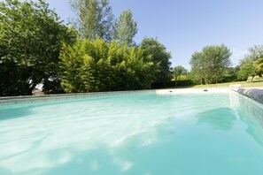 A clear swimming pool surrounded by lush greenery and trees. - Heated pool, single-storey, rural location. Near restaurants and historic towns (Pardaillan)