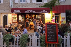 Un restaurante con terraza, un cartel que anuncia 'Parrillada de Poissons et Crustacés', y un toldo rojo con la inscripción 'Chateau Molhieres'.