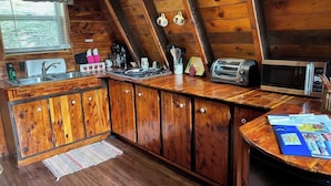 A wooden kitchen with a built-in sink, a toaster, and a microwave.