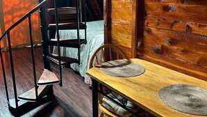 A wooden dining area with a spiral staircase, a clock, and a framed picture on the wall.