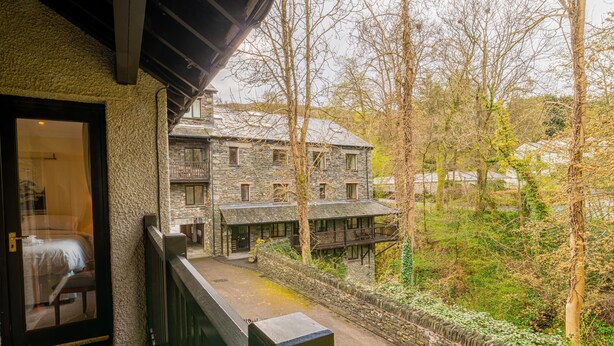 A stone building with a balcony overlooking a garden and a pathway. - Tree Tops at The Falls -  3-bedroom duplex, stroll into Ambleside (Ambleside)
