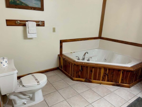 A bathroom with a wooden bathtub, a toilet, and a white sink.