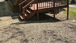 Eine Holzhütte mit grüner Dachdeckung und einer Holzterrasse, verbunden durch eine Treppe zum Eingang.