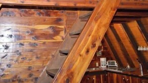 Ein Dachzimmer aus Holz mit schrägen Wänden, Holzbalken und einem Oberlicht.