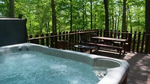 A hot tub on a wooden deck surrounded by a wooden fence, with a table and chairs nearby.