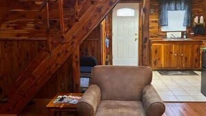 A wooden interior with a sofa, ottoman, and a staircase.
