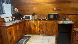 A kitchen with wooden cabinets, a microwave, a toaster, and a refrigerator.
