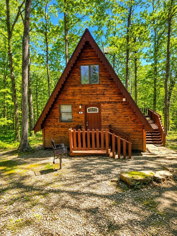 A wooden cabin with a porch, a mailbox, and a staircase leading to the entrance.
