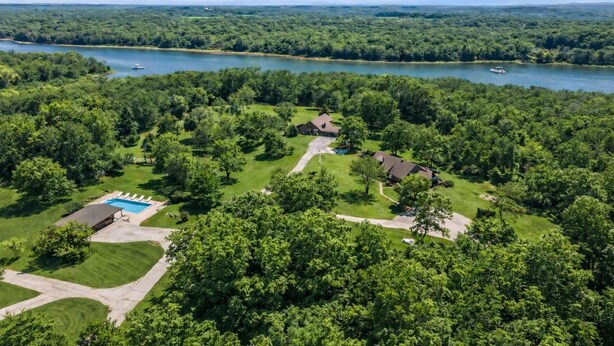 An aerial view of a residential area with a swimming pool, multiple houses, and a lake.