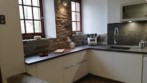 A kitchen with stone accents, a built-in stove, and a modern sink. - Maison Le Pijoulet, Dream vacation in Ariege (TIGNAC)