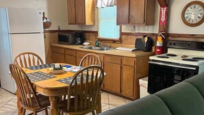 Una cocina compacta con armarios de madera, una mesa de comedor con sillas, una estufa y un microondas.
