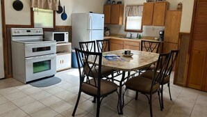 Une cuisine compacte avec un coin repas, comprenant une cuisinière, un four à micro-ondes, un réfrigérateur et des placards en bois.