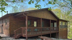Une cabane en bois avec une véranda, une table de pique-nique et un sol en gravier.