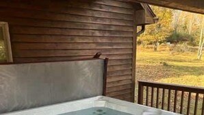 Ein Whirlpool mit einer Holzterrasse und Blick auf eine Wiese.