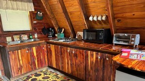 Una cocina con armarios de madera, microondas, tostadora y una alfombra estampada.
