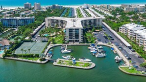 Uma marina com barcos, quadra de tênis e um hotel com telhado curvo.