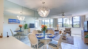 Uma área de jantar moderna com uma mesa de vidro, cadeiras de vime e um lustre decorativo.