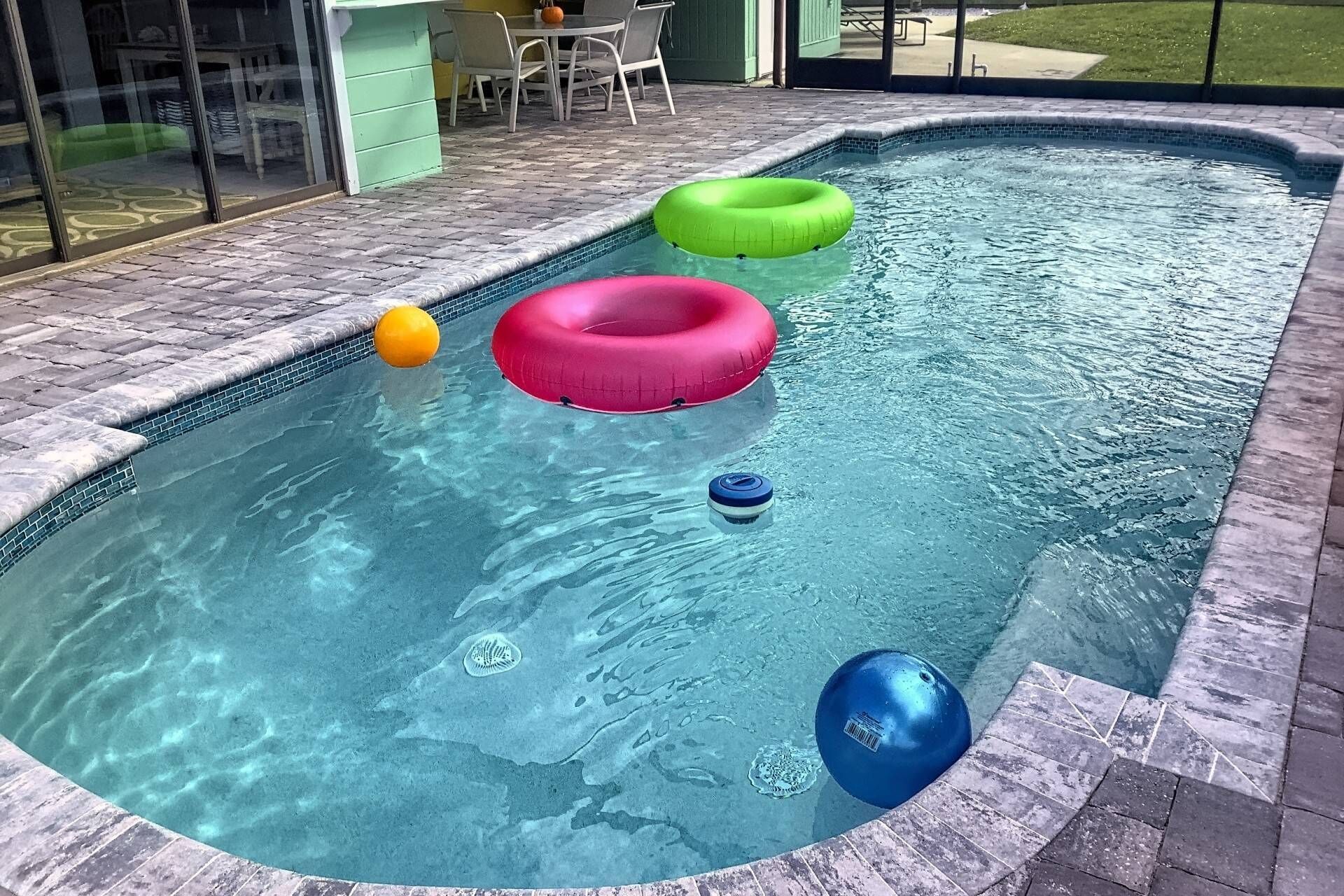Una piscina con tres flotadores y un juguete acuático azul.