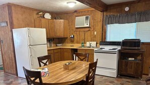 Cocina compacta con gabinetes de madera, un refrigerador, un microondas y una estufa.