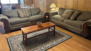 Una sala de estar acogedora con dos sofás, una mesa de centro de madera y una alfombra estampada.