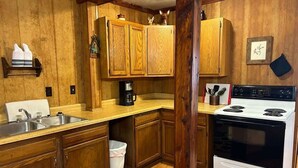 Una cocina con armarios de madera, una estufa blanca y una cafetera.