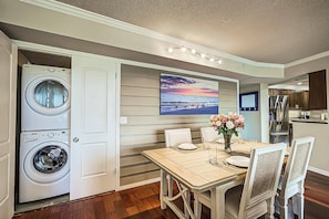 A compact kitchen with modern appliances, a dining area with a table set for two, and a large window with a view of the ocean.
