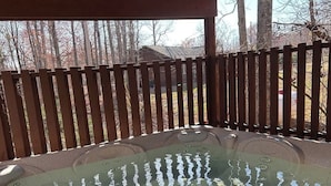 Un jacuzzi bajo una pérgola de madera, con una valla de madera al fondo.