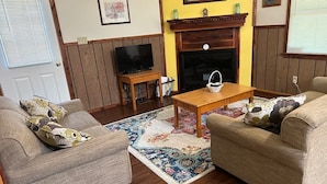 Una sala de estar con dos sofás, una mesa de centro, una chimenea y un televisor.