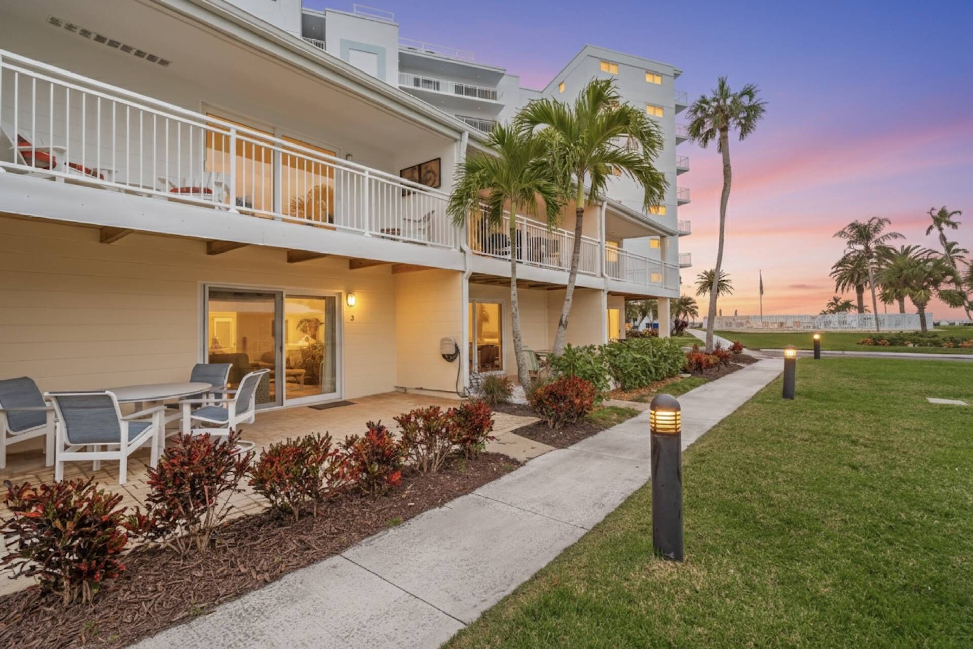 A hotel with a covered outdoor area, multiple balconies, and a view of the sunset.