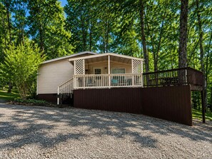 A single-story mobile home with a porch and a fenced yard.