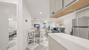 Una cocina moderna con armarios blancos, encimera de mármol y refrigerador empotrado.