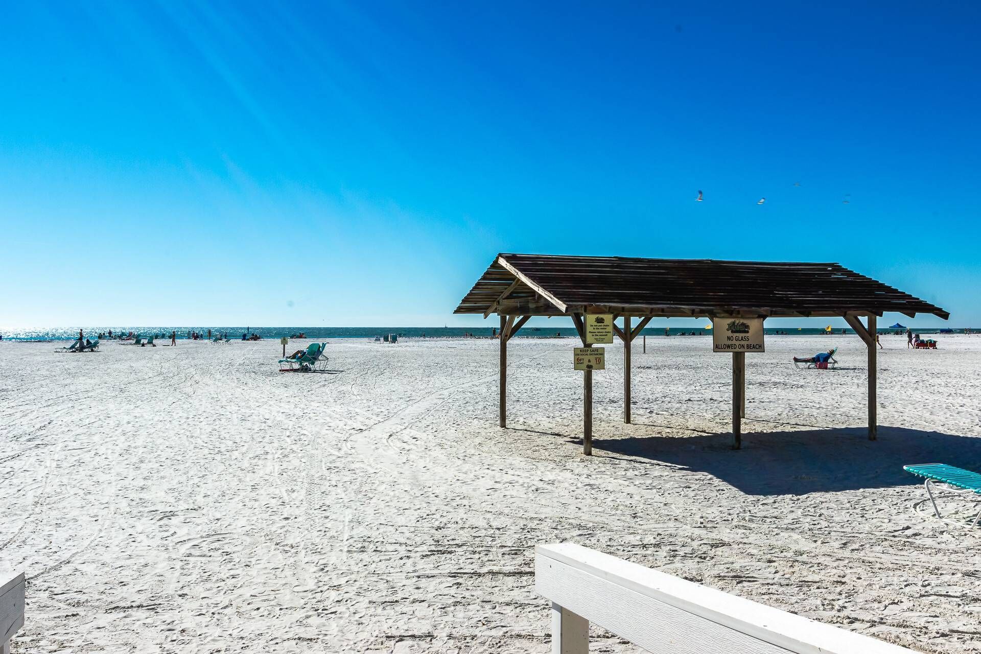 A beach with a wooden shelter, clear skies, and a sandy shore.